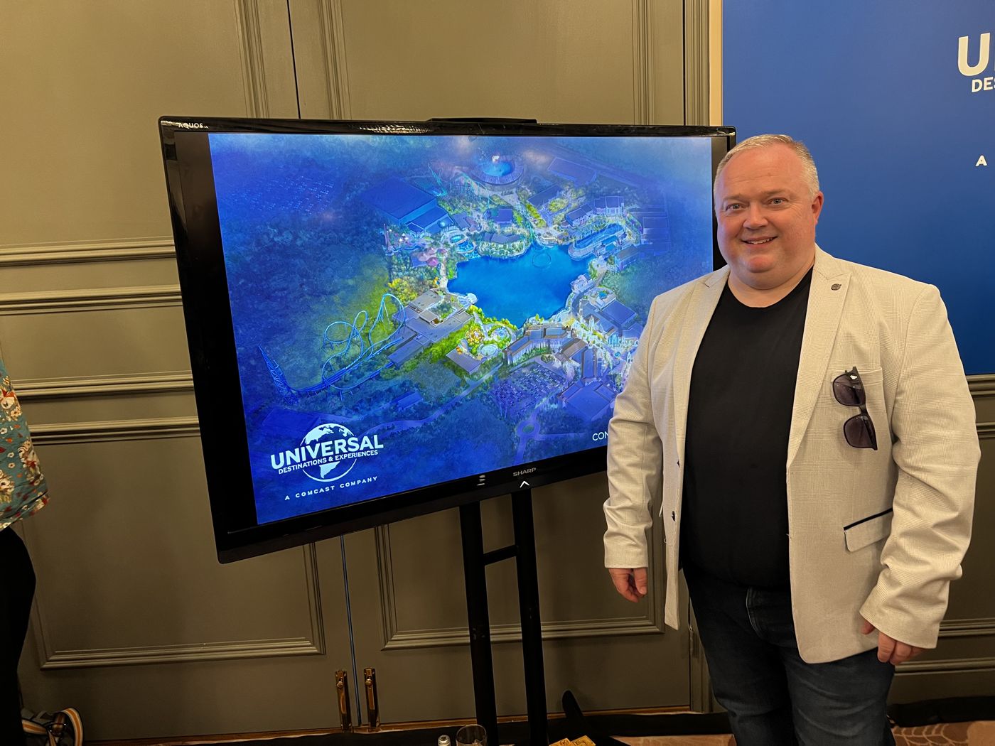 Leigh at the Universal United Kingdom briefing, beside a screen showing the resort plans